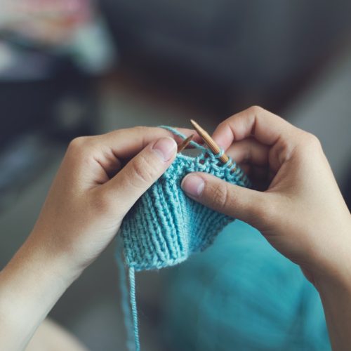person's hands knitting